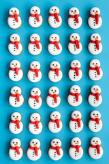 Wall Mural - Gingerbread snowmen covered with icing on a blue background, flat lay.