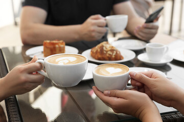 Sticker - Friends drinking coffee at wooden table in outdoor cafe, closeup