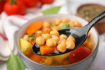 Eating tasty chickpea soup on table, closeup