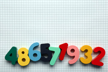 Colorful numbers on sheet of grid paper, flat lay. Space for text