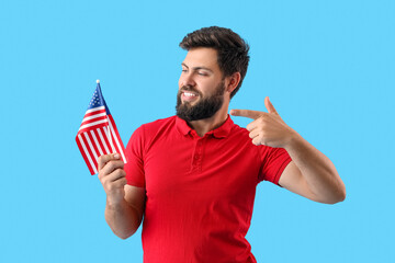 Handsome bearded man pointing at USA flag on blue background