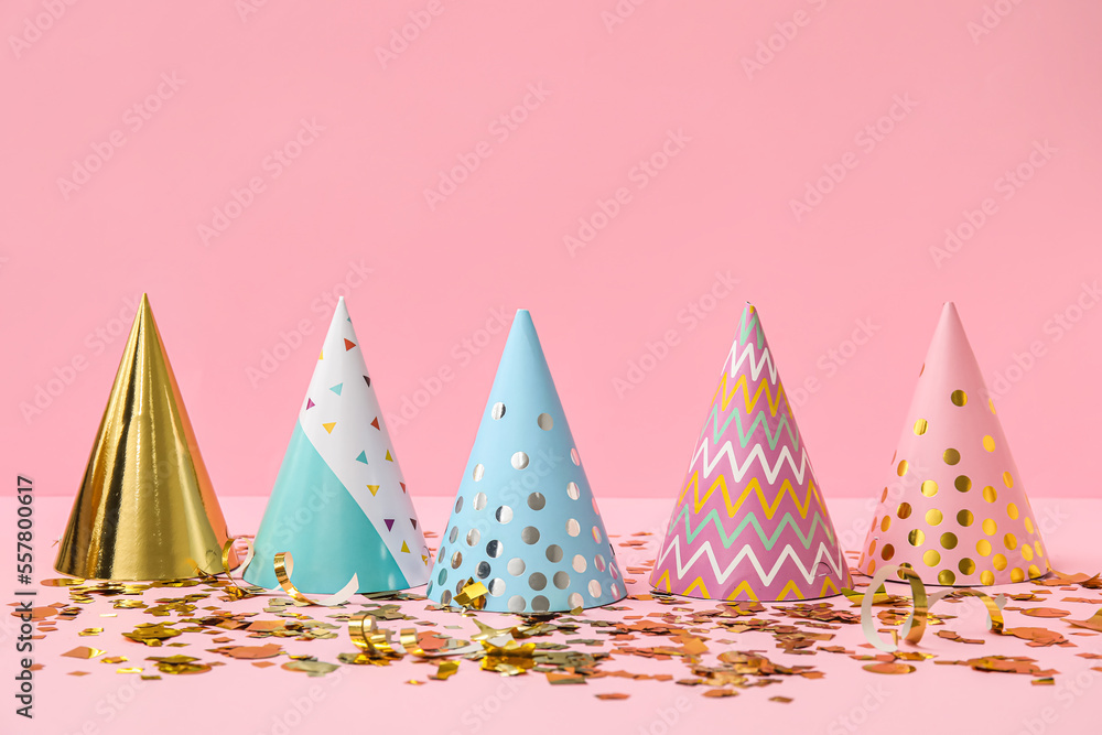 Party hats and confetti on pink background