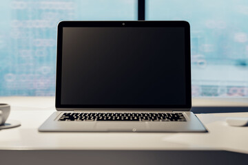 Front view on blank black modern laptop monitor screen with space for your logo or text on light table surface with coffee mug and blurred window background, closeup. 3D rendering, mock up