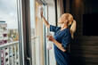 © Dusan Petkovic - A happy maid is cleaning windows in hotel room with detergent and cloth.