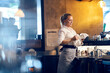 © Dusan Petkovic - A blond female professional bartender is cleaning glass in a bar while standing behind a bar counter.
