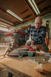 © ADDICTIVE STOCK - Carpenter cutting wood on circular saw table