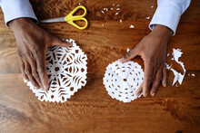 Hands Of Man Holding Paper Snowflakes On Table