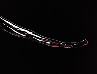 Flow of Crude Oil gasoline pour down over dark background isolated. Black water liquid fall down line. Black Ink, Coffee drink pour splash drop as gold crude oil or sticky water