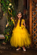 Elegant beauty little girl in yellow dress and gloves standing in decorated mystical room. Fashionable stylish princess smiling looking at camera. Fantasy art photo, fairy tale concept. Copy space