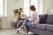© Studio Romantic - Happy teen patient talking to psychologist about positive emotions during therapy session. Preteen girl shows woman paper with smiley emoticon drawn on it and describes emotions she feels.