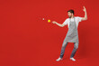 © ViDi Studio - Full body young happy male housewife housekeeper chef cook baker man wearing grey apron hold vegetables on skewer play pov fight fencing isolated on plain red background studio Cooking food concept