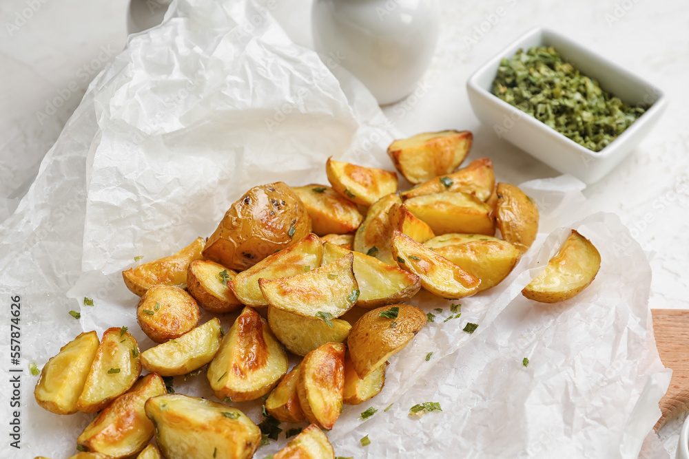 Baking paper with delicious baked potato on table, closeup