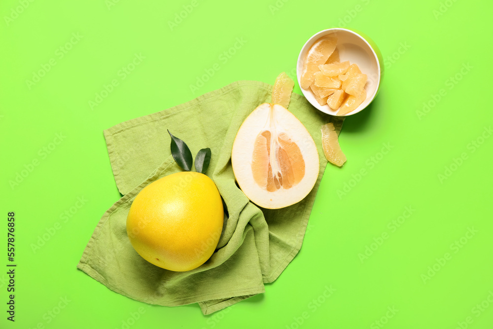 Whole and cut pomelo fruit on green background