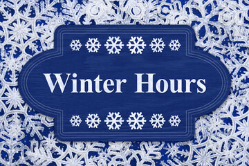 Wall Mural - Winter Hours blue wood sign on white snowflakes
