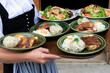 © Юлия Усикова - The waiter holds national Bavarian dishes, bread dumplings, meat and cabbage on a tray.