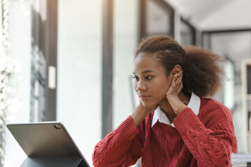 Wall Mural - Smiling African American Hispanic student looking up from laptop at campus library, using tablet and feeling serious