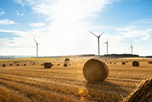 Wind Turbines In A Field With Bales Of Straw