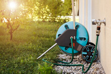 Hose With Faucet Outdoor For Watering. Lawn Sprinkler Attached To Mobile Garden Hose Reel And Brass Tap Outside.