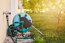 Garden Hose Coil Connected To External Faucet On Wall For Watering Or Irrigation Garden. Mobile Hose Coil With Tap Outdoor