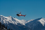 A helicopter taken in flight in front of a snowy mountain panorama