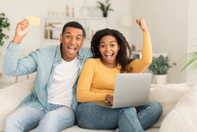 Glad Millennial African American Couple With Laptop, Credit Card Make Victory, Success Gesture With Hand
