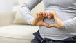 © Andrii - Cropped photo of pregnant woman shows a heart shape on her stomach with her hands