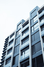 A Grey Blue Facade Of A Modern Multistory Residential Building, House View From A Bottom Up. Home Details Of The Exterior, Architecture Of A Metropolis. Construction, Real Estate Investment Concept.