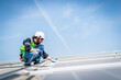 © SKW - Male engineer installing or checking the working condition of solar panels on the roof or at the height of the factory for saving electricity was broken to use renewable energy from the sun