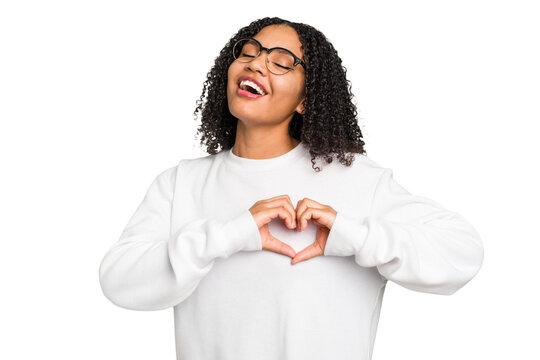 Young african american woman with curly hair cut out isolated smiling and showing a heart shape with hands.