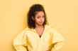 © Asier - Young Brazilian curly hair cute woman isolated on yellow background confused, feels doubtful and unsure.