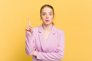 Wall Mural - Young caucasian redhead woman isolated on yellow background having some great idea, concept of creativity.