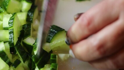 Canvas Print - hand with knife cuts cucumber on board