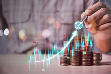 Poster - man hand holding a pen draw business graph target over coins stack background, business and financial concept