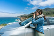 © PR Image Factory - side portrait of asian chinese professional woman photographer on California road trip taking pictures of scenery at seaside with slr camera by her car