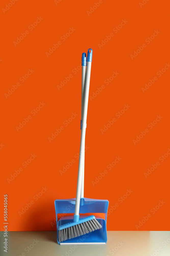 Dustpan and cleaning broom on floor near color wall