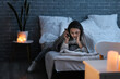 © Pixel-Shot - Young woman reading book with flashlight in bedroom during blackout