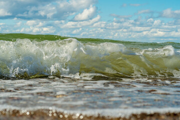 Close-up of an approaching sea wave. Positive joyful background on the theme of a fun beach holiday, vacation and travel. Healthy marine recreation. Bright sunny day on a warm seashore.