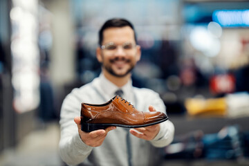 Wall Mural - Selective focus on man's hands showing shoe in shoe store.