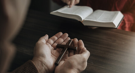 Closeup of simple wooden Christian cross necklace on Bible. Concept of hope, faith, christianity, religion.