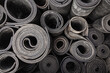 Old sheet rubber of black color, twisted into rolls, top view. rubber waste.