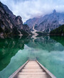 canvas print picture - Holz Treppe in einen grünen und türkisen Bergsee in dem sich Berge spiegeln.