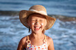 Happy Children Sea Holiday. Smiling Child Girl Sunbathing with Sunscreen on Face in Blue Sea Background. Funny Positive Kid in the Sea