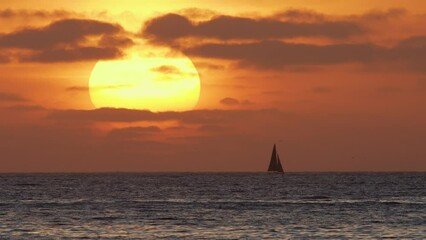 Wall Mural - Beautiful evening sunset with a big sun and a sailing yacht in the Atlantic Ocean on the coast of Portugal. 