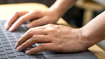 Wall Mural - Action of a businessperson is typing on the modern design laptop keyboard to input or program data, business working concept scene. Close-up and selective focus at human hand's part.