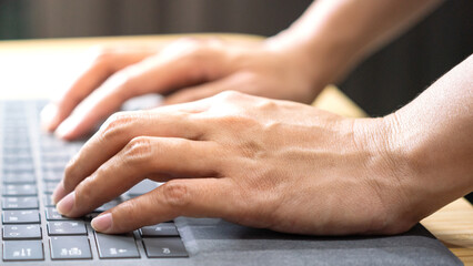 Wall Mural - Action of a businessperson is typing on the modern design laptop keyboard to input or program data, business working concept scene. Close-up and selective focus at human hand's part.