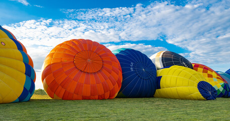 several bright balloons are inflated on the ground before the flight at the festival