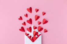 Saint Valentine Day Greeting Card With Love Message. Envelope And Paper Red Hearts On Pink Background Top View. Flat Lay.