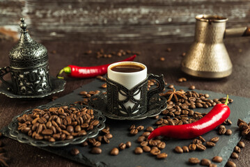 Wall Mural - traditional turkish coffee in vintage cup, anise, roasted beans with hot spicy chili pepper on brown background