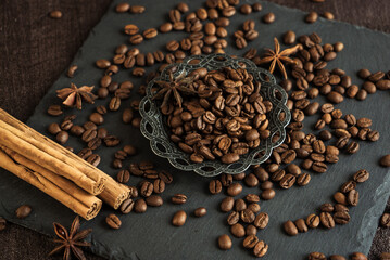 Wall Mural - roasted coffee beans with spices, anise and cinnamon sticks in a metal turkish bowl on a black background 4