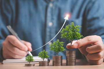 Businessman holding trees growing on increasing coins stacking for money saving and deposit growth from investment profit , Financial banking concept.